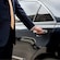A private driver opening the door of a luxury sedan